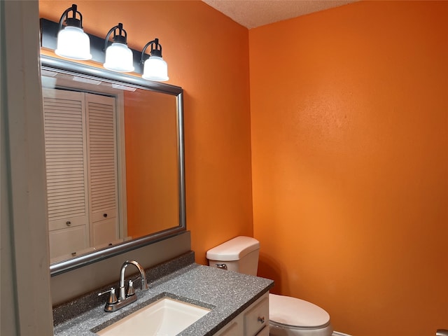 bathroom featuring a textured ceiling, vanity, and toilet