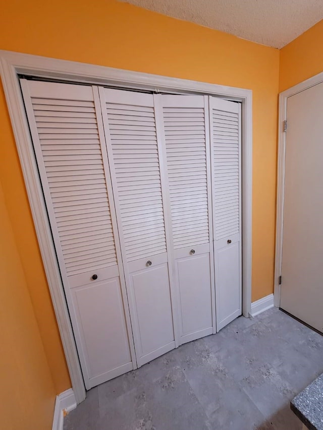 details with concrete flooring, a textured ceiling, and baseboards