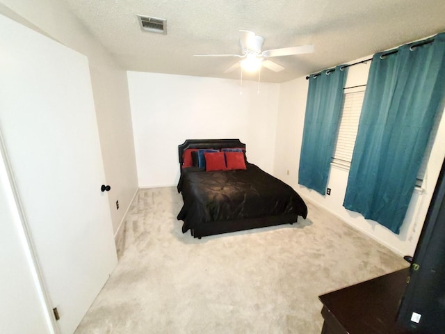 bedroom featuring carpet floors, a ceiling fan, visible vents, and a textured ceiling