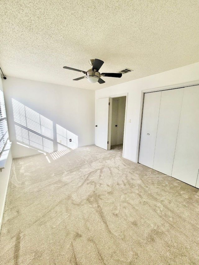 unfurnished bedroom featuring a textured ceiling, ceiling fan, and light colored carpet