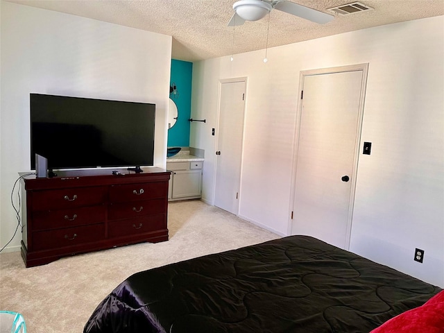 bedroom featuring a textured ceiling, visible vents, and light colored carpet