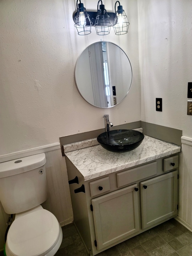 bathroom featuring wooden walls, vanity, and toilet