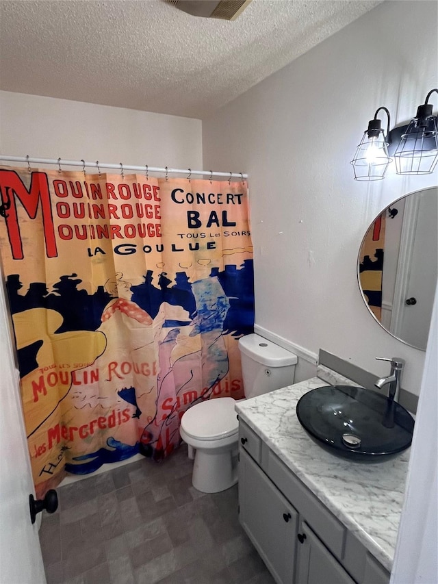 bathroom with curtained shower, vanity, toilet, and a textured ceiling