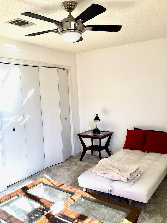 carpeted bedroom featuring a textured ceiling, a closet, visible vents, and a ceiling fan