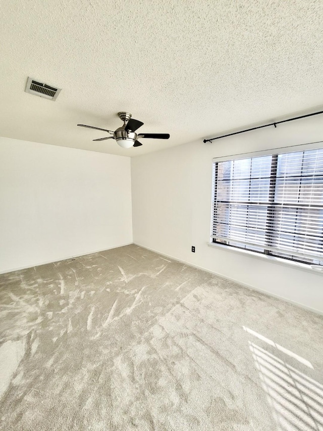 unfurnished room with a ceiling fan, a textured ceiling, visible vents, and carpet flooring