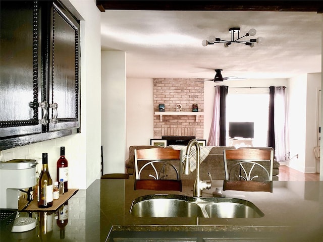 kitchen with a brick fireplace, a ceiling fan, and a sink