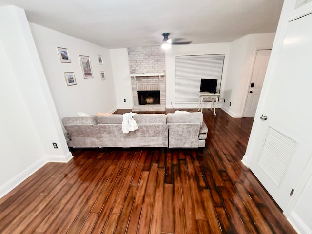 living room featuring ceiling fan, a fireplace, and dark hardwood / wood-style flooring