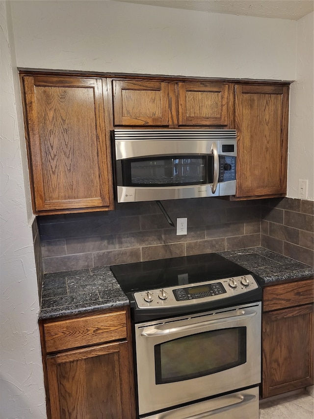 kitchen with dark stone counters, stainless steel appliances, and tasteful backsplash