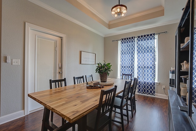 dining room with a raised ceiling, crown molding, and dark hardwood / wood-style flooring