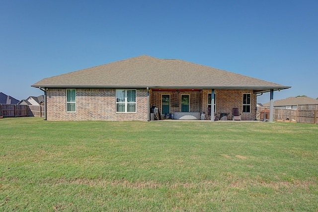 rear view of house featuring a lawn and a patio