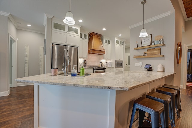 kitchen featuring white cabinetry, stainless steel appliances, dark hardwood / wood-style floors, custom range hood, and a breakfast bar area