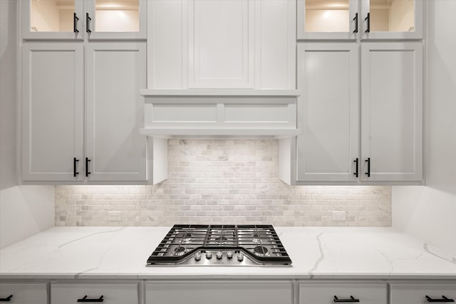 kitchen featuring light stone countertops, decorative backsplash, white cabinetry, and stainless steel gas cooktop