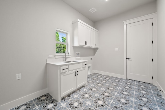 clothes washing area featuring hookup for a washing machine, sink, electric dryer hookup, and cabinets