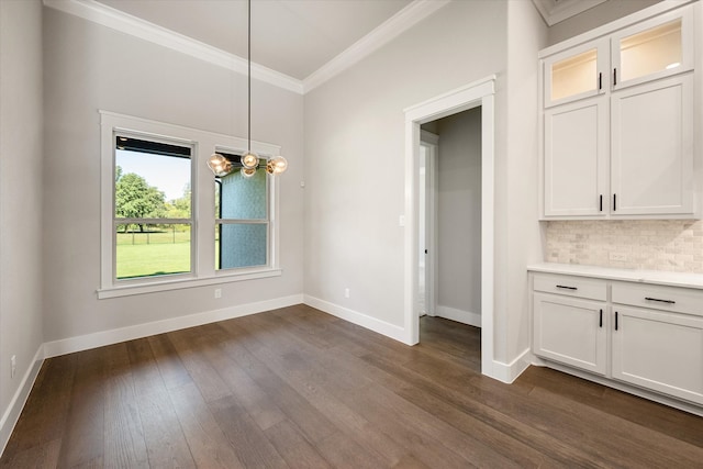 unfurnished dining area with ornamental molding, an inviting chandelier, and dark wood-type flooring