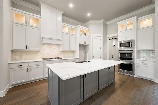 kitchen featuring light stone countertops, white cabinetry, an island with sink, and dark hardwood / wood-style flooring