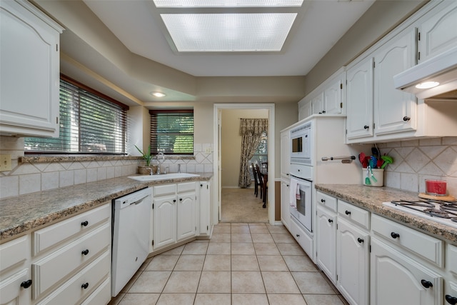 kitchen featuring white cabinets, white appliances, light tile patterned flooring, and sink