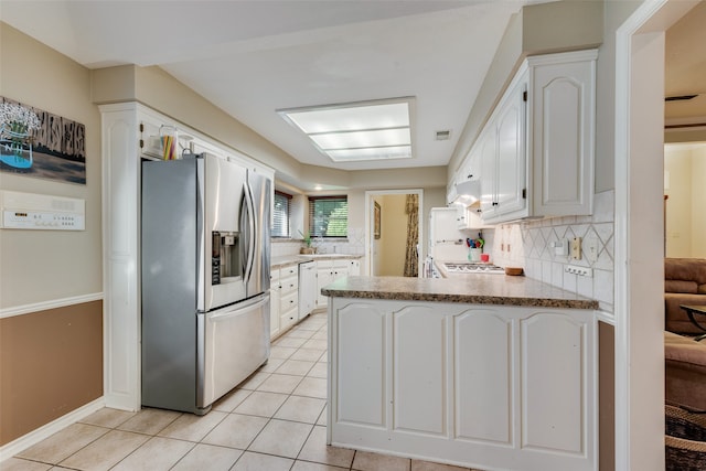 kitchen with white cabinets, stainless steel fridge, kitchen peninsula, and light tile patterned floors