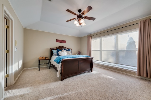 bedroom featuring light carpet, a tray ceiling, and ceiling fan