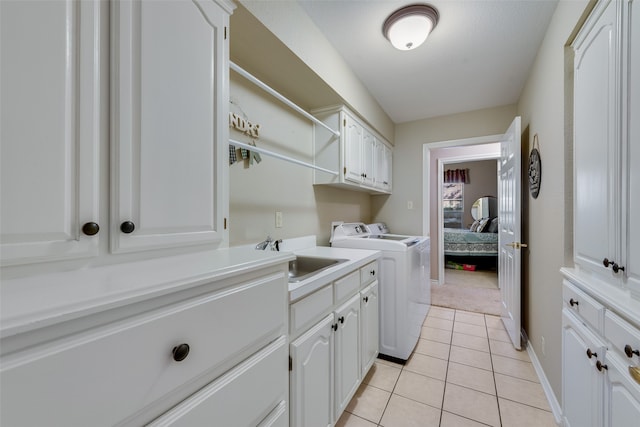 laundry room with washing machine and dryer, sink, light tile patterned floors, and cabinets