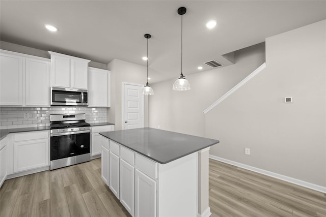 kitchen with decorative light fixtures, a center island, appliances with stainless steel finishes, decorative backsplash, and white cabinets