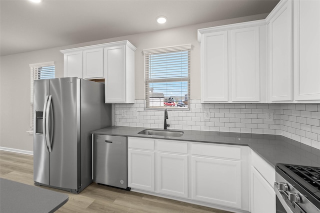 kitchen with sink, light hardwood / wood-style floors, white cabinets, and appliances with stainless steel finishes