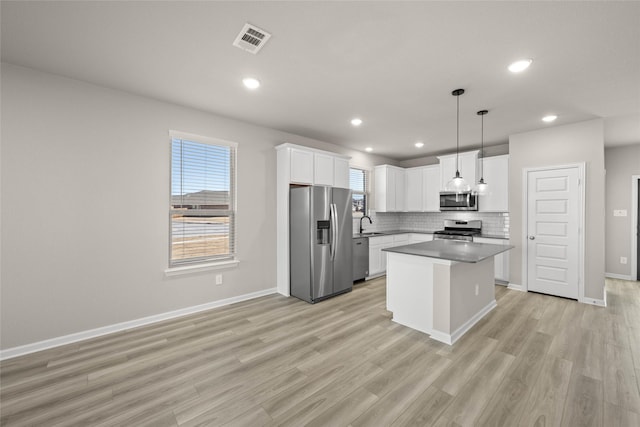 kitchen with pendant lighting, white cabinetry, a center island, stainless steel appliances, and light hardwood / wood-style flooring