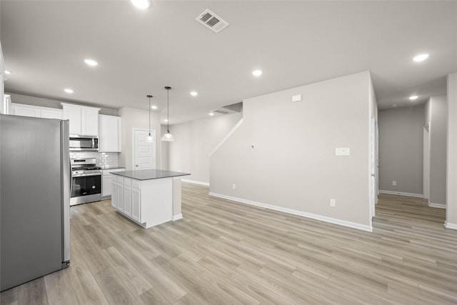 kitchen with stainless steel appliances, a center island, hanging light fixtures, and white cabinets