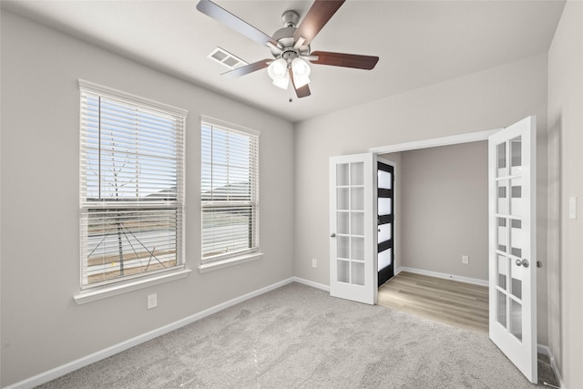 carpeted empty room featuring french doors and ceiling fan