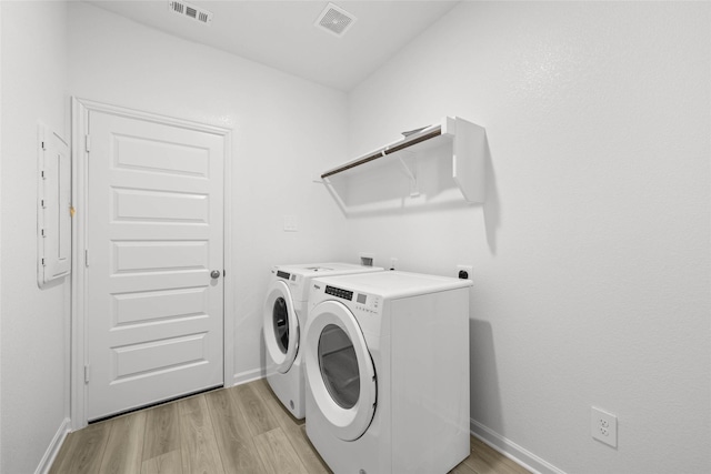 washroom with washing machine and clothes dryer and light wood-type flooring