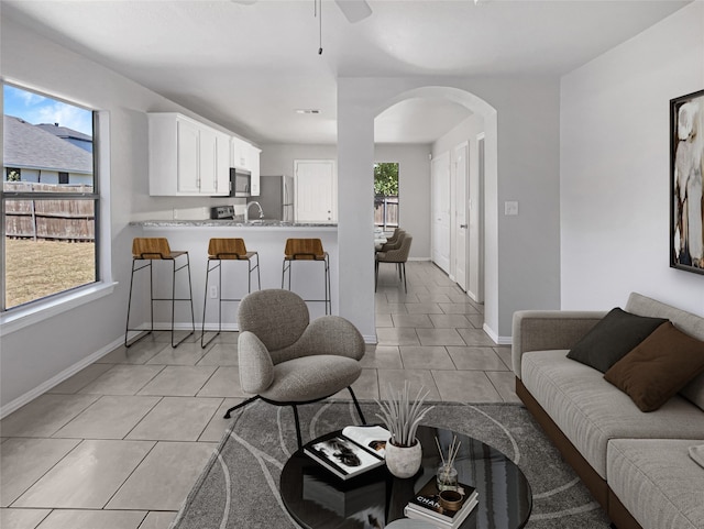 living room featuring ceiling fan, sink, and light tile patterned floors