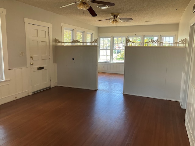 unfurnished room with ceiling fan, a textured ceiling, plenty of natural light, and dark hardwood / wood-style floors