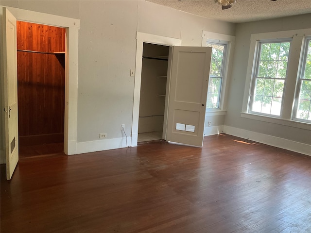 unfurnished bedroom with a textured ceiling and dark hardwood / wood-style floors