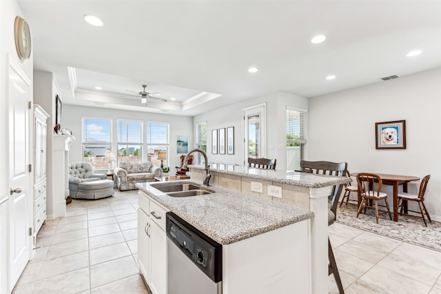 kitchen featuring ceiling fan, sink, white cabinetry, dishwasher, and a kitchen bar