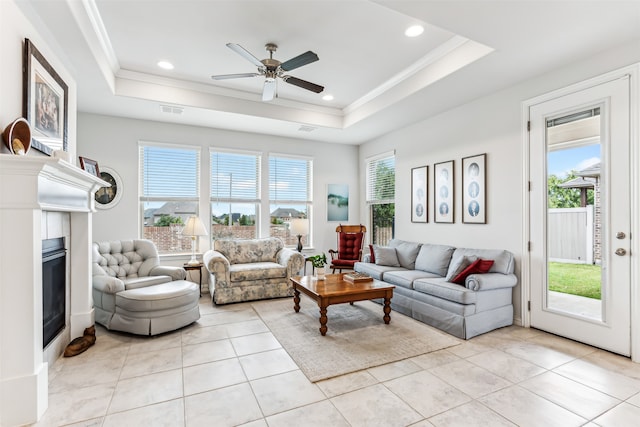 tiled living room featuring a raised ceiling, ornamental molding, and ceiling fan