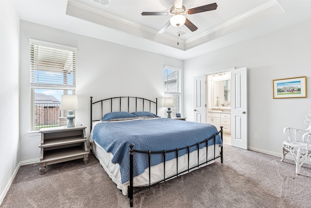 bedroom with ceiling fan, a raised ceiling, ensuite bathroom, and multiple windows