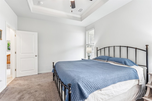 bedroom featuring ceiling fan, a tray ceiling, light carpet, and crown molding