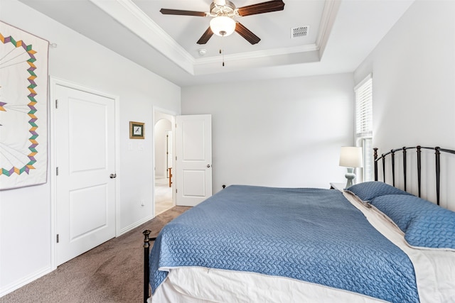 carpeted bedroom with ceiling fan, a raised ceiling, and crown molding