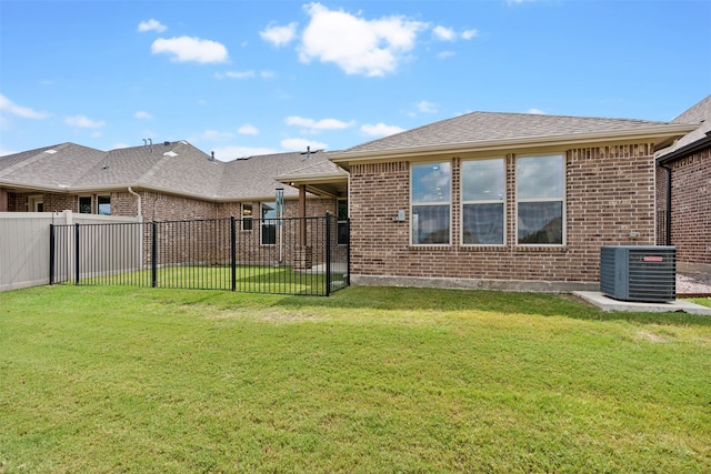 rear view of house with a lawn and central AC