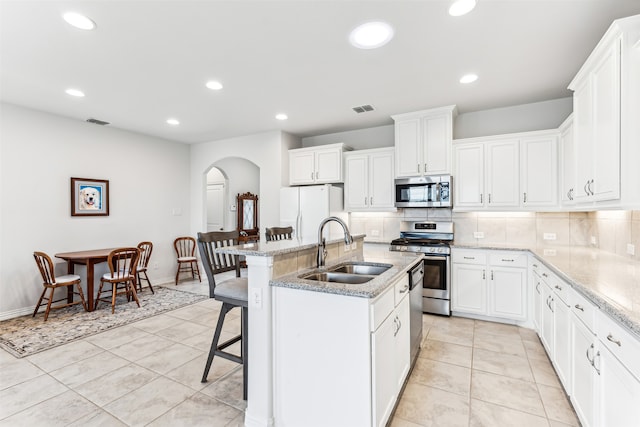 kitchen featuring white cabinets, sink, a kitchen island with sink, appliances with stainless steel finishes, and a breakfast bar