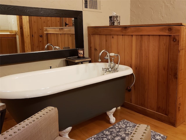 bathroom featuring wood-type flooring, wood walls, and a tub