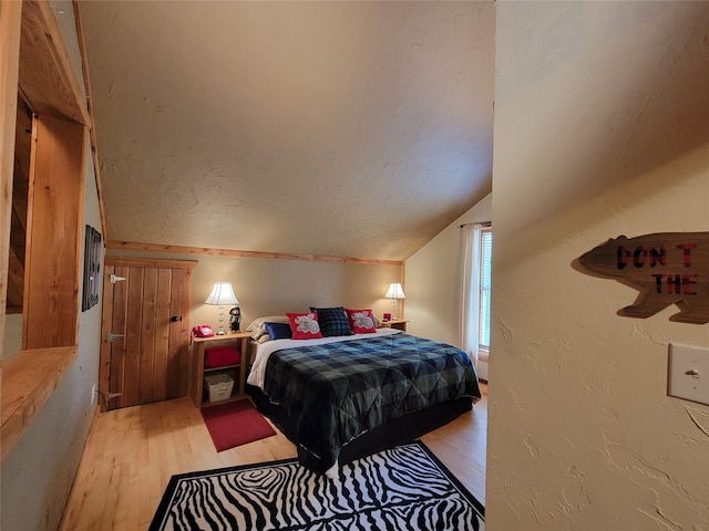 bedroom with light wood-type flooring and lofted ceiling