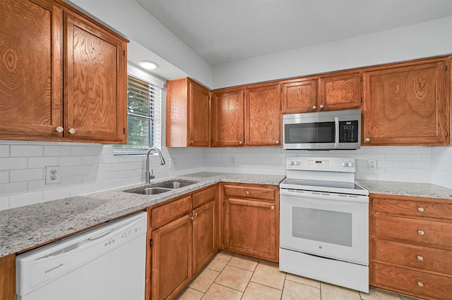 kitchen with light tile patterned floors, backsplash, sink, and white appliances