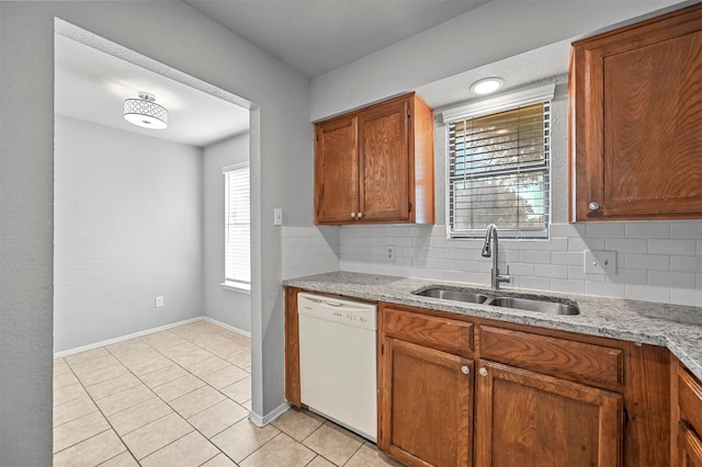 kitchen with dishwasher, light stone counters, tasteful backsplash, sink, and light tile patterned floors