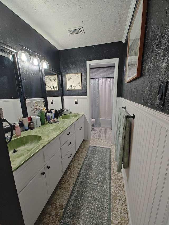 bathroom with a textured ceiling, vanity, and toilet