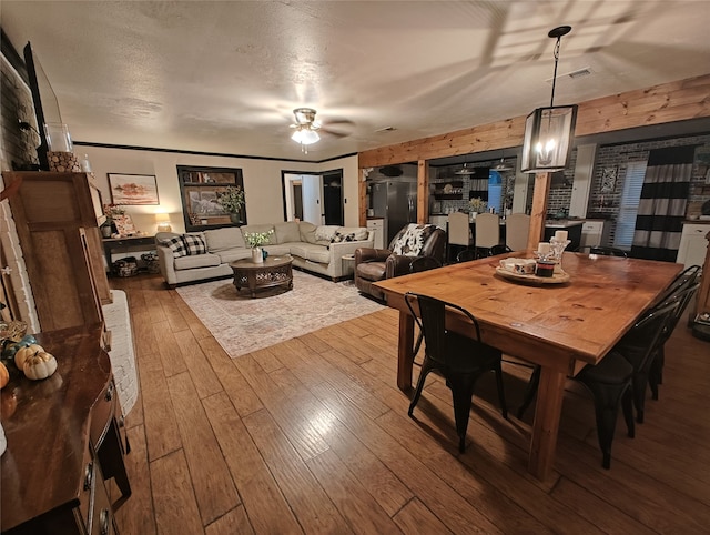 dining space with ceiling fan, hardwood / wood-style flooring, and a textured ceiling