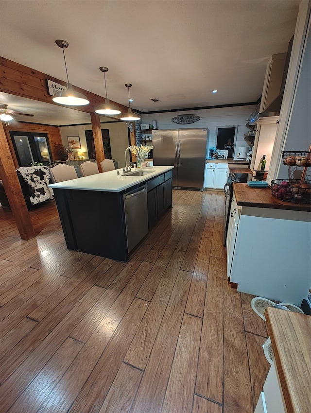 kitchen with pendant lighting, dark hardwood / wood-style floors, sink, an island with sink, and appliances with stainless steel finishes