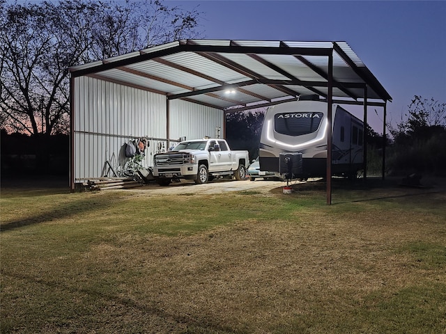 outdoor structure at dusk featuring a lawn and a carport