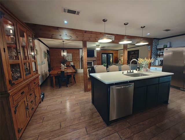 kitchen featuring hardwood / wood-style flooring, a kitchen island with sink, sink, stainless steel appliances, and decorative light fixtures