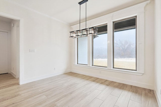 unfurnished room with an inviting chandelier, light hardwood / wood-style flooring, and crown molding