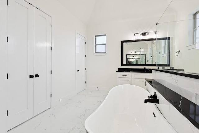 bathroom featuring vanity, lofted ceiling, and a tub